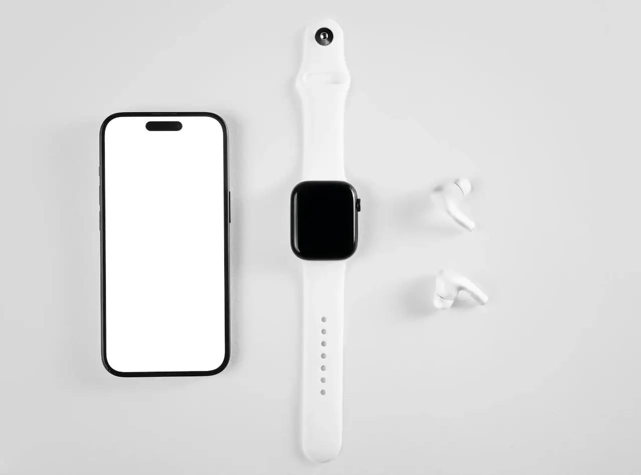 Smartwatch, smartfon i bezprzewodowe słuchawki ułożone na jasnym tle, symbolizujące kompatybilność urządzeń mobilnych z systemem Android.