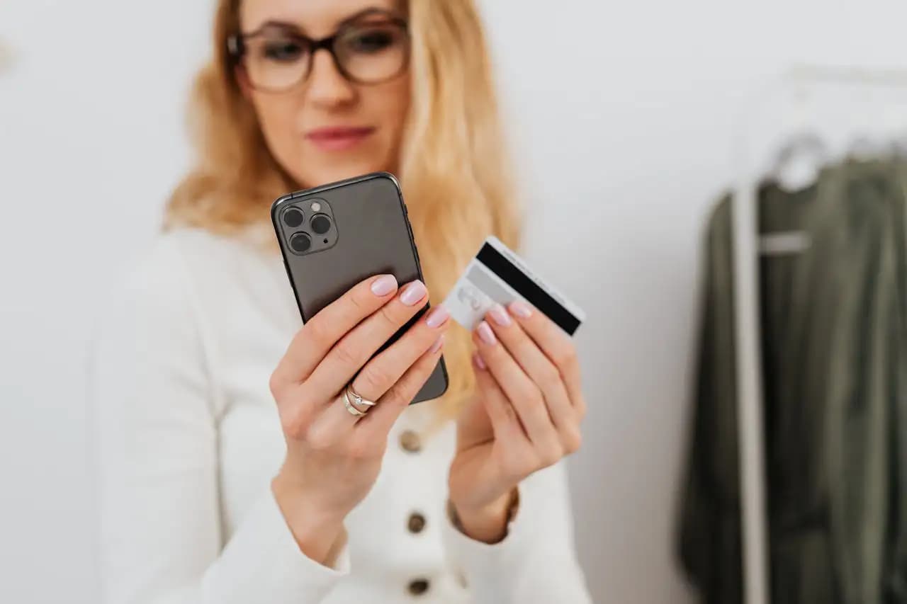 Kobieta trzymająca smartfon i kartę płatniczą, konfiguracja płatności mobilnych na telefonie