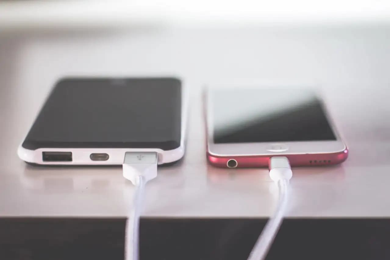 Smartfon z uszkodzonym portem ładowania podłączony do kabla USB – naprawa portu ładowania i alternatywne metody zasilania.