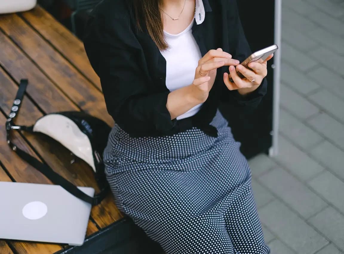 Kobieta trzymająca smartfon w dłoniach i sprawdzająca jego działanie, symbolicznie ilustrująca problem z czujnikiem zbliżeniowym w telefonie.