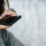 Kobieta trzyma w dłoniach smartfon z całkowicie czarnym, niedziałającym ekranem.