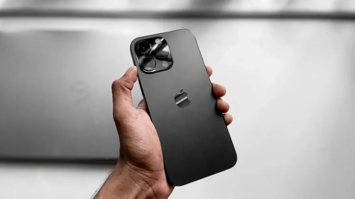 elefon trzymany w dłoni na szarym tle, symbolizujący problem z połączeniem Bluetooth w smartfonie.