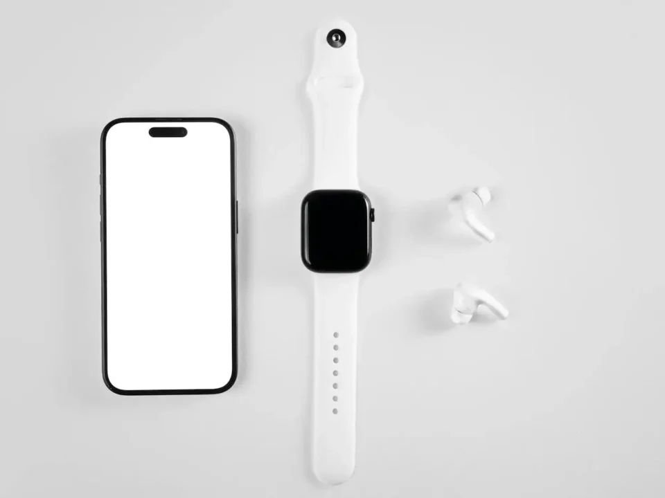 Smartwatch, smartfon i bezprzewodowe słuchawki ułożone na jasnym tle, symbolizujące kompatybilność urządzeń mobilnych z systemem Android.