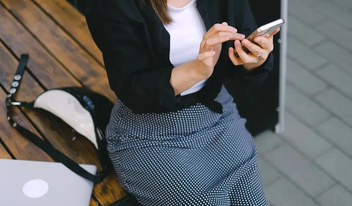 Kobieta trzymająca smartfon w dłoniach i sprawdzająca jego działanie, symbolicznie ilustrująca problem z czujnikiem zbliżeniowym w telefonie.