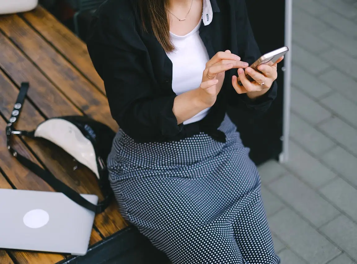 Kobieta trzymająca smartfon w dłoniach i sprawdzająca jego działanie, symbolicznie ilustrująca problem z czujnikiem zbliżeniowym w telefonie.